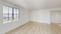 This contemporary apartment in Boca Raton, Florida, offers 990 square feet of thoughtfully designed living space. The open-concept floor plan seamlessly integrates the kitchen, living, and dining areas, creating a spacious feel. The kitchen is a highlight, featuring sleek white cabinetry, stainless steel appliances, and a large island with pendant lighting.

Light wood-look flooring flows throughout, complementing the crisp white walls and enhancing the bright, airy ambiance. Large windows and a sliding glass door leading to a balcony flood the space with natural light and provide city views.

The primary bedroom, measuring 150 square feet, offers ample space and includes a well-appointed en-suite bathroom. A second bedroom and bathroom provide comfortable accommodations for guests or a home office setup. Both bathrooms feature modern fixtures and tiled surroundings, with at least one including a bathtub-shower combination.

Storage is plentiful, with two closets and additional built-in shelving. The unit also includes in-unit laundry facilities for added convenience. Overall, this apartment combines style and functionality in a desirable Boca Raton location.