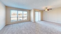 Located at 2457 N Peterson Ct in Louisville, Kentucky, this two-story home offers a practical and comfortable layout across both levels. The kitchen is outfitted with warm-toned wood cabinetry, light granite-style countertops, and black appliances including a range, built-in microwave, dishwasher, and refrigerator. Dark hardwood-style flooring grounds the kitchen and extends into adjacent areas, providing a clean contrast to the neutral wall tones throughout.

The living areas are generously sized and carpeted, benefiting from abundant natural light through large windows and sliding glass doors fitted with vertical blinds. A ceiling fan adds comfort to the main living space, which also features a textured ceiling. An open railing with black metal balusters and a pendant light marks the transition between floors, adding a subtle architectural detail.

Bedrooms are carpeted and include closets with double bi-fold doors and built-in hanging rods, offering practical storage. Additional walk-in closet space is also present. The bathroom features wood-style vinyl flooring, a wood-tone vanity, and a tiled tub-shower combination. Overall, the home presents a neutral, move-in ready aesthetic with functional finishes throughout.