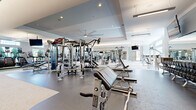 Located at 2600 Prairie Winds Dr in St. Charles, IL, this expansive fitness center is a fully equipped, single-floor facility designed to support a wide range of workout styles and fitness goals. The space is organized into several distinct training zones, each thoughtfully appointed with professional-grade equipment.

The strength training area is the centerpiece of the facility, housing a comprehensive array of Hammer Strength and cable machines, multi-station cable systems, free weight benches, and an extensive dumbbell rack. Large wall mirrors amplify the sense of space and assist with form, while ceiling fans and recessed lighting maintain a comfortable environment.

A dedicated functional training zone features TRX suspension trainers, weighted sleds, battle ropes, stability balls, and a turf surface — ideal for athletic conditioning and dynamic workouts. An additional section offers a variety of selectorized machines for targeted muscle training.

The cardio area is lined with large windows that invite abundant natural light and outdoor views, and is equipped with treadmills, ellipticals, stair climbers, and rowing machines, all accompanied by wall-mounted flat-screen TVs. The flooring transitions between rubberized surfaces and carpet depending on the zone, offering both durability and comfort. The facility is accessible via glass-door entry and maintains a clean, modern aesthetic throughout.