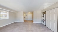 Located at 402 Westover Hills Blvd in Richmond, VA, this single-floor unit offers a practical and well-organized layout encompassing a living room, kitchen, and full bathroom. The living room is bright and open, finished with light-toned laminate wood flooring and neutral beige walls that create a clean, airy feel. Large windows and a glass-paneled front door flood the space with natural light while offering outdoor views of the surrounding greenery. A pair of spacious double closet doors provides generous built-in storage, and a stacked washer and dryer unit is conveniently integrated into the living area. The kitchen is efficiently arranged with white cabinetry, dark granite-style countertops, a stainless steel sink, and a gas range, all complemented by a window that brings in additional natural light. The bathroom features a full-size soaking tub and shower combination with a clean white surround with built-in shelving niches, paired with a white vanity. Throughout the unit, consistent laminate flooring and a neutral color palette tie the rooms together cohesively, making the space feel polished and move-in ready.