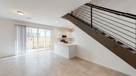 This well-appointed two-story home offers a clean, modern aesthetic throughout both levels. The main floor welcomes you with a bright, open-concept layout featuring large-format tile flooring that flows seamlessly from the entry through the living area and kitchen. A striking open-riser staircase with a sleek black metal railing serves as a focal point, adding a contemporary design element to the space. The kitchen is outfitted with crisp white shaker cabinetry, light countertops, and a full suite of stainless steel appliances, including a refrigerator, range, microwave, and dishwasher. A peninsula provides additional prep space and casual seating. Sliding glass doors off the main living area open to an outdoor patio, inviting natural light deep into the interior. A conveniently located half bathroom on the main level features gold-toned fixtures and a white vanity. Upstairs, the carpeted bedrooms offer a comfortable and quiet retreat, with windows that bring in natural light. The primary bedroom includes a generously sized walk-in closet with built-in shelving and hanging rods. The full upstairs bathroom is finished with tile flooring, a walk-in shower with a decorative mosaic tile accent strip, a white vanity, and gold hardware throughout, lending a cohesive and refined touch to the space.