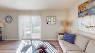 Located at 100 Kimball Ave. in Salem, Virginia, this single-floor residence offers a well-organized layout designed for comfortable, everyday living. The living room serves as the heart of the home, featuring warm hardwood-style flooring that flows throughout the main areas. Large sliding glass doors allow generous natural light to fill the space while providing direct access to an outdoor area, creating an open, airy atmosphere. The kitchen is thoughtfully equipped with light wood cabinetry, dark countertops, and white appliances including a dishwasher, range, and built-in microwave. Hardwood-style flooring continues here, complementing the neutral, practical design. Two bedrooms offer restful retreats, each with plush carpeting and windows that bring in natural light. The primary bedroom includes a ceiling fan and ample space, while the secondary bedroom maintains a cozy, comfortable feel with its own window. The bathroom features a light wood vanity, a large wall mirror with overhead lighting, built-in open shelving, and neutral toned finishes that contribute to a clean, functional aesthetic. Throughout the residence, neutral wall tones and consistent design choices create a cohesive and inviting environment suitable for a variety of lifestyles.