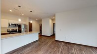 This single-floor residence features a contemporary design with a cohesive blend of modern finishes and functional layout. The open-concept living and kitchen area is anchored by rich wood-look plank flooring and clean white walls, creating a bright, inviting atmosphere. The kitchen is well-appointed with stainless steel appliances, including a full-size refrigerator, electric range, and built-in microwave. White upper cabinetry contrasts with darker lower cabinets, while granite-style countertops extend across the peninsula, which also features a double sink — ideal for both meal preparation and casual dining.

The bedrooms offer plush carpeting and generous natural light. One bedroom features a floor-to-ceiling corner window with expansive outdoor views, while another provides direct outdoor access through a sliding glass door fitted with vertical blinds and a ceiling fan. The unit includes two full bathrooms, each finished with neutral tile flooring, dark wood vanities, white countertops, and large mirrors. One bathroom features a shower-tub combination. Dark wood-tone doors and dark baseboards throughout provide a polished, modern contrast to the neutral walls and light ceilings.