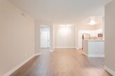 This single-floor unit presents a cohesive, contemporary design throughout, anchored by rich dark hardwood-style flooring that flows seamlessly across the living areas and bedrooms. Neutral warm-gray wall tones create a versatile backdrop, complemented by crisp white trim and baseboards throughout.

The open-concept layout connects the living area directly to the kitchen, which features white shaker-style cabinetry, light quartz countertops, a subtle tile backsplash, and a full suite of stainless steel appliances including a refrigerator, range, microwave, and dishwasher. A peninsula counter provides additional workspace and separation between the kitchen and living area.

The living room benefits from a sliding glass door that opens to a private balcony, allowing natural light and outdoor views of surrounding greenery to fill the space. Multiple bedrooms offer windows with exterior views, maintaining a bright and airy atmosphere.

Two bathrooms are finished with white cabinetry, quartz countertops, tub-shower combinations, and chrome fixtures. One bathroom includes built-in shelving for additional storage. A dedicated laundry area houses a full-size top-loading washer and dryer beneath overhead white cabinetry, adding practical convenience to the unit.