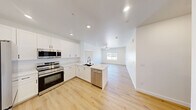 Located at 2555 N Rancho Dr in Las Vegas, NV, this well-appointed single-floor residence offers three bedrooms and two bathrooms across a thoughtfully designed layout. The open-concept kitchen serves as the heart of the home, featuring crisp white shaker cabinetry, a large peninsula with striking marble-veined quartz countertops, a deep undermount sink, and a full suite of stainless steel appliances including a range, microwave, and dishwasher. The kitchen flows seamlessly into a bright, airy living area illuminated by recessed lighting and a ceiling fan, with a window that brings in natural light. Light-toned wood-look flooring runs consistently throughout the entire home, lending a clean and cohesive aesthetic. The primary bedroom offers a comfortable footprint with a dedicated closet, while the additional bedrooms are well-sized, each with ceiling fans and ample closet space. The two bathrooms are finished with marble-style quartz vanity tops and chrome fixtures; one features a walk-in glass-door shower, and the other includes a full tub-shower combo with subway tile surround. A dedicated laundry area houses a full-size side-by-side washer and dryer with overhead shelving. The home's modern, neutral palette and clean finishes create a bright and move-in-ready living environment.