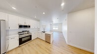 Located at 2555 N Rancho Dr in Las Vegas, NV, this well-appointed single-floor residence offers three bedrooms and two bathrooms across a thoughtfully designed layout. The open-concept kitchen serves as the heart of the home, featuring crisp white shaker cabinetry, a large peninsula with striking marble-veined quartz countertops, a deep undermount sink, and a full suite of stainless steel appliances including a range, microwave, and dishwasher. The kitchen flows seamlessly into a bright, airy living area illuminated by recessed lighting and a ceiling fan, with a window that brings in natural light. Light-toned wood-look flooring runs consistently throughout the entire home, lending a clean and cohesive aesthetic. The primary bedroom offers a comfortable footprint with a dedicated closet, while the additional bedrooms are well-sized, each with ceiling fans and ample closet space. The two bathrooms are finished with marble-style quartz vanity tops and chrome fixtures; one features a walk-in glass-door shower, and the other includes a full tub-shower combo with subway tile surround. A dedicated laundry area houses a full-size side-by-side washer and dryer with overhead shelving. The home's modern, neutral palette and clean finishes create a bright and move-in-ready living environment.
