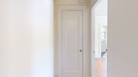 Located in the Westlake neighborhood of Los Angeles, this three-bedroom, one-bathroom unit on the third floor offers a thoughtfully laid-out single-level floor plan with timeless architectural character. Rich hardwood floors extend throughout the living areas and all three bedrooms, adding warmth and continuity to the space. The generously sized primary bedroom features a ceiling fan, natural light from a set of windows, and access to an adjacent vanity area, offering a touch of vintage charm. The additional bedrooms are well-proportioned, each with their own window for natural light, and one includes a classic cast-iron radiator. The kitchen retains its period character with white cabinetry featuring glass-front uppers, a classic double-basin sink with wall-mounted fixtures, subway tile backsplash, and a bold black-and-white checkered tile floor that extends into the connecting hallway. The bathroom continues the vintage aesthetic with full white subway tile walls, penny tile flooring, a pedestal sink, and a soaking tub beneath a bright window with a view of the surrounding greenery. Multiple hallways connect the rooms efficiently, and the overall palette of crisp white walls against warm wood floors gives the unit a clean, classic feel throughout.