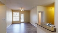 Located at 927 VFW Blvd in San Antonio, TX, this single-floor unit offers a practical and comfortable layout across several well-defined living spaces. The living room serves as the heart of the home, featuring smooth hardwood-style flooring, a ceiling fan, and a glass door alongside a large window that invites abundant natural light and provides outdoor views. The kitchen is efficiently designed with a U-shaped layout, featuring dark lower cabinetry contrasted by white upper cabinets, granite-style countertops, a double stainless steel sink, and white appliances including a refrigerator and electric range. The bedrooms are carpeted for comfort, each equipped with a ceiling fan and generously sized windows that bring in natural light. One bedroom includes a walk-in closet, adding practical storage. The unit includes two full bathrooms, both finished with wood-style flooring, dark vanity cabinetry, granite-style countertops, and large mirrors. One bathroom features a tiled tub-shower combination, while the other offers a shower area. Warm neutral wall tones throughout create a cohesive, inviting atmosphere across every room.