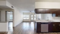 This single-floor residence offers a thoughtfully designed open-concept layout that seamlessly connects the kitchen and living areas. The kitchen is outfitted with dark espresso cabinetry, stainless steel appliances including a microwave and refrigerator, and a peninsula-style island with a light countertop that doubles as a casual dining or workspace. Wood-style flooring runs consistently throughout the unit, lending warmth and visual continuity to every room.

The spacious living area is a highlight of the home, featuring a classic fireplace as a focal point, French doors that open to an outdoor balcony, and a large window that floods the space with natural light. A ceiling fan adds both style and function to the room.

The bedrooms are generously sized, each featuring ceiling fans, wood-style flooring, and windows fitted with blinds for privacy and light control. The clean, neutral white walls throughout provide a versatile backdrop adaptable to any décor style.

Additional practical features include a dedicated laundry area with washer/dryer hookups and wire shelving for storage. The overall ambiance is clean, modern, and move-in ready, offering a comfortable and functional living environment.
