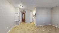 Located at 1802 N Rockwell Ave in Bethany, Oklahoma, this single-story, one-bedroom, one-bathroom unit offers a practical and straightforward layout across its single floor. The living room is finished with light-toned ceramic tile flooring and neutral gray walls, creating a clean and open atmosphere. A white six-panel entry door provides access and contributes to the room's bright feel, complemented by a textured ceiling overhead.

The galley-style kitchen is efficiently designed, featuring white cabinetry, a white electric range, a black refrigerator, and a sink with ample counter space. The tile flooring continues seamlessly from the living area into the kitchen, maintaining visual consistency throughout the main spaces.

A hallway connects the main living areas to the bedroom and bathroom. The bedroom is generously proportioned, finished with wall-to-wall carpet for added comfort, and includes a ceiling fan with integrated lighting. A window allows natural light to filter in, enhancing the room's warmth. A closet provides dedicated storage space.

The bathroom is straightforward and functional, featuring a tiled tub-and-shower combo with chrome fixtures. Neutral tones carry throughout the unit, giving the space a cohesive and understated aesthetic. Overall, the unit presents a clean, no-frills living environment suitable for practical everyday use.