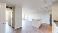 Located at 640 Main Street in Saskatoon, Saskatchewan, this 1-bedroom, 1-bathroom unit offers a clean, modern design with a thoughtfully laid-out open-concept floor plan. The combined kitchen and living area provides a seamless flow, anchored by light-toned laminate flooring that runs throughout the space. The kitchen is well-appointed with white cabinetry, granite countertops, a central island with additional granite surface space, stainless steel appliances including a refrigerator, electric range, microwave, and dishwasher, plus track lighting and a pendant light above the island. The living area is generous and bright, benefiting from large sliding glass doors that open onto a private balcony offering pleasant views of surrounding greenery and trees. Baseboard heating runs along the perimeter walls, ensuring comfort throughout the seasons. The bathroom features a full soaker tub surrounded by clean white subway tile, with wood-look tile flooring adding a warm touch. The unit's neutral white walls and abundant natural light create a fresh, airy atmosphere, making this a functional and inviting space in a well-situated Saskatoon address.