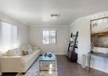 Located at 574 Button Ave in Manteca, California, this single-story home offers a thoughtfully designed interior with a cohesive modern aesthetic throughout. The living room is bright and welcoming, featuring dark hardwood-style flooring, crisp crown molding, and a window that brings in natural light and views of the surrounding landscape. The space feels comfortable and well-proportioned, ideal for everyday living and entertaining.

The kitchen is a standout feature, outfitted with rich dark cabinetry, white countertops, a double-basin sink, and black appliances including a refrigerator and range. The galley-style layout maximizes functionality, while light wood-tone flooring adds warmth to the space. An open pass-through connects the kitchen to the dining area, which is finished with hardwood-style floors, crown molding, and a ceiling fan, making it an inviting spot for meals.

The bedrooms are carpeted and serene, with crown molding and natural light from well-placed windows. The primary bedroom is spacious and relaxed in tone. The bathroom is clean and modern, featuring a dark wood vanity with white countertop, a large mirror, and a tub-shower combination. Throughout the home, neutral tones, consistent trim details, and quality finishes create a polished and livable environment.