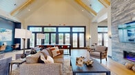 Located at 1875 Maple Dr in Kennesaw, Georgia, this expansive single-story community clubhouse offers an impressive and thoughtfully designed gathering space. The interior is anchored by soaring vaulted ceilings with exposed natural wood beams and white shiplap paneling, creating a bright, airy atmosphere throughout the open floor plan.

The main lounge area features generous seating arrangements with plush sofas and accent chairs set atop layered area rugs over wide-plank light hardwood flooring. Floor-to-ceiling dark-framed windows and glass doors flood the space with natural light while offering views of the surrounding community. A striking stone accent wall serves as a dramatic backdrop for a mounted flat-screen display and fireplace, flanked by comfortable seating clusters.

A central bar island with a bold navy base, white marble countertop, and leather barstools takes center stage in one section of the space, illuminated by elegant gold pendant chandeliers and accented by a textured tile feature wall. A billiards table nearby adds a recreational element.

Additional areas include a dedicated co-working zone with long communal tables, a built-in desk nook set against a vibrant blue accent wall, and a reception area with a marble-topped counter framed by a navy shiplap feature wall with integrated shelving and a television. The entry foyer welcomes visitors with swivel accent chairs and expansive glass entry doors.