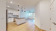 This single-floor, 3-bedroom, 1-bathroom home offers a thoughtfully designed layout that balances comfort and functionality. The open-concept kitchen and living area serves as the heart of the home, featuring light hardwood flooring that flows seamlessly throughout the main living spaces. The kitchen is well-equipped with white shaker cabinetry, a classic subway tile backsplash, dark granite countertops, stainless steel appliances including a French door refrigerator, and a central island with pendant lighting overhead — ideal for both meal preparation and casual dining. The adjoining living room is bright and airy, benefiting from natural light streaming through large windows and a glass door that provides outdoor access, complemented by a ceiling fan above. Each of the three bedrooms is carpeted for comfort and includes a ceiling fan, with windows dressed in white blinds that invite natural light and outdoor views. The primary bedroom offers a generous footprint with a closet for ample storage. The bathroom features wood-look flooring and clean, minimal finishes. Throughout the home, crisp white walls, consistent trim work, and a neutral palette create a fresh, modern ambiance ready for personalization.