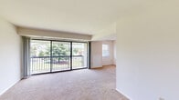 Located at 2402 Cowan Blvd in Fredericksburg, VA, this one-bedroom, one-bathroom unit offers a thoughtfully organized single-floor layout. The entrance opens into a hallway that connects the main living areas, creating a logical and functional flow throughout the space. The combined living and dining room is the heart of the unit, featuring plush carpeting, neutral walls, and a wall of floor-to-ceiling sliding glass doors that flood the room with natural light and provide direct access to a private balcony overlooking lush greenery. The kitchen features a breakfast bar peninsula, ample cabinetry, and durable countertops, making it a practical space for everyday cooking. The spacious bedroom is carpeted and benefits from a dedicated window that brings in additional natural light. A standout feature of the bedroom is its exceptional storage, with multiple closets fitted with bifold doors lining the walls. The bathroom includes a full tub-shower combination with clean white tile surround. Throughout the unit, a mix of wood-style hard flooring in the entry areas and soft carpet in the living and sleeping spaces adds warmth and visual contrast. Three closets in total ensure abundant storage throughout the home.