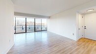 Located on the eighth floor at 1550 Clarendon Blvd in Arlington, VA, this thoughtfully designed 2-bedroom, 2-bathroom residence offers a bright and modern living experience. The open living and dining area is a standout, featuring floor-to-ceiling sliding glass doors that flood the space with natural light and provide sweeping views of the Arlington skyline. Light-toned hardwood-style flooring flows throughout, enhancing the airy, contemporary feel. The living area connects seamlessly to a private balcony, perfect for taking in the urban panorama. The galley-style kitchen is well-appointed with dark cabinetry, light countertops, stainless steel appliances, and recessed lighting, balancing style with functionality. The generously sized primary bedroom includes its own sliding glass door to the balcony and abundant natural light, while the second bedroom features a large window with outdoor views. Both bathrooms are finished with sleek dark vanities, white countertops, and backlit mirrors. Additional conveniences include two closets and an in-unit laundry area with a full-size washer and dryer. The clean, minimalist design and elevated position make this a compelling urban residence.