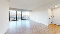 Located on the eighth floor at 1550 Clarendon Blvd in Arlington, VA, this thoughtfully designed 2-bedroom, 2-bathroom residence offers a bright and modern living experience. The open living and dining area is a standout, featuring floor-to-ceiling sliding glass doors that flood the space with natural light and provide sweeping views of the Arlington skyline. Light-toned hardwood-style flooring flows throughout, enhancing the airy, contemporary feel. The living area connects seamlessly to a private balcony, perfect for taking in the urban panorama. The galley-style kitchen is well-appointed with dark cabinetry, light countertops, stainless steel appliances, and recessed lighting, balancing style with functionality. The generously sized primary bedroom includes its own sliding glass door to the balcony and abundant natural light, while the second bedroom features a large window with outdoor views. Both bathrooms are finished with sleek dark vanities, white countertops, and backlit mirrors. Additional conveniences include two closets and an in-unit laundry area with a full-size washer and dryer. The clean, minimalist design and elevated position make this a compelling urban residence.