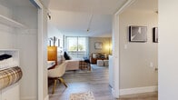 Located in the heart of Midtown Sacramento at 415 P St, this efficiently designed one-bedroom, one-bathroom unit offers a thoughtful layout across a single floor. Light wood-tone flooring runs throughout, creating a cohesive and clean aesthetic. The open-plan living area seamlessly connects the kitchenette, dining, and lounge spaces. The kitchenette features white shaker-style cabinetry, a marble-look tile backsplash, an under-counter refrigerator, and a compact island with a butcher block top and bar seating — ideal for casual dining. The living area accommodates a full seating arrangement, with warm-toned furnishings and wall art adding character. The spacious bedroom is a standout, anchored by floor-to-ceiling windows and a sliding glass door that opens to a balcony, allowing abundant natural light and views of the surrounding cityscape. A dedicated workspace and ample room for storage furnishings make the bedroom highly functional. The bathroom is clean and well-appointed, featuring a white vanity with a framed mirror, updated fixtures, and light flooring that maintains the unit's neutral palette. A closet provides additional storage. The textured ceiling and recessed entry hallway complete the space's practical, modern character.