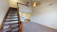 Located at 1237 Watermark Dr in Lancaster, Ohio, this two-story home offers a practical and comfortable layout across two floors. The main level features a functional kitchen equipped with wood-toned cabinetry, white appliances including a refrigerator and electric range, a double sink set into a peninsula counter, and durable hardwood-style flooring. The layout provides a convenient flow between the kitchen and adjoining areas.

The upper floor hosts three carpeted bedrooms, each finished with neutral walls, wood trim baseboards, and standard ceiling-mounted light fixtures. The generously sized primary bedroom features vaulted ceilings and a ceiling fan, adding an open, airy feel, along with a window that allows natural light to filter in. The additional bedrooms are well-proportioned with windows overlooking the surroundings. A walk-in closet with built-in shelving provides ample storage.

The upper hallway connects the bedrooms to the full bathroom, which includes a tub and shower combination with a grab bar, a vanity with mirror, and hardwood-style flooring. A staircase links both floors, and the overall interior maintains a clean, neutral palette throughout, making it a versatile and move-in ready home.