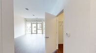Located at 115 E Walnut St in downtown Green Bay, Wisconsin, this efficient single-floor unit offers a well-designed layout comprising a living room, kitchen, bathroom, and closet. The living area is bright and open, featuring warm wood-tone flooring and large floor-to-ceiling windows that flood the space with natural light and offer views of the surrounding urban streetscape. The clean white walls and neutral palette create a modern, airy ambiance throughout.

The kitchen is thoughtfully appointed with dark espresso cabinetry, stainless steel appliances including a refrigerator, electric range, microwave, and dishwasher, as well as a tile backsplash and ample cabinet storage. The wood flooring continues seamlessly from the living area into the kitchen, reinforcing a cohesive, contemporary aesthetic.

The bathroom features light stone-look tile flooring, a walk-in shower stall, vanity with dark cabinetry, and built-in shelving, providing practical storage in a clean, neutral finish. A dedicated closet with hanging rods and shelving offers additional organization. The unit also includes a programmable thermostat for climate control. Overall, the space presents a clean, modern design well-suited for efficient urban living in the heart of Green Bay.