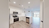 Located at 175 Black St in Rock Hill, SC, this well-appointed 1-bedroom, 1-bathroom unit offers a thoughtfully designed single-level layout with modern finishes throughout. The open-concept kitchen and living area serves as the heart of the home, featuring white shaker cabinets with gold hardware, a white subway tile backsplash, a peninsula with a matte black sink and pendant lighting, and a full suite of stainless steel appliances. Light wood-look flooring runs throughout the main living areas, complementing the bright, neutral color palette. The living area flows seamlessly to a private balcony through sliding glass doors, offering outdoor views and natural light. The bedroom is carpeted for comfort and includes a dedicated walk-in closet. A flexible office space and additional closet provide practical storage and work-from-home options. The full bathroom is finished with marble-style tile, a soaking tub, built-in niche, and oil-rubbed bronze fixtures paired with white cabinetry and countertops. A dedicated laundry area and utility room add everyday convenience. Recessed lighting throughout ensures a clean, contemporary ambiance across the entire space.