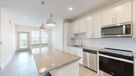 Located in Bradenton, FL, this 2-bedroom, 2-bathroom single-floor residence offers a thoughtfully designed open layout with modern finishes throughout. The kitchen serves as the centerpiece of the home, boasting a large granite-topped island with pendant lighting overhead, crisp white shaker cabinetry, a subway tile backsplash, and a full suite of stainless steel appliances including a range, microwave, dishwasher, and refrigerator. Light wood-style flooring flows through the kitchen and connects seamlessly to the bright living area, which features recessed lighting and a glazed door opening to an outdoor balcony, allowing ample natural light to fill the space. The primary bedroom is generously sized, fitted with soft carpeting, dual windows with blinds, and a ceiling fan. It connects to a private bathroom with a granite vanity, tile-surround tub and shower, and wood-style flooring, as well as a dedicated walk-in closet with wire shelving. The second bedroom also features carpet and a sun-filled window. A second full bathroom mirrors the refined finishes of the primary bath. Two closets provide practical storage throughout the home, completing this clean and contemporary residence.