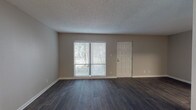 This single-floor residence offers a thoughtfully designed layout with a clean, modern aesthetic throughout. The open living area features dark hardwood-style flooring and a textured ceiling, with a sliding glass door that fills the space with natural light and provides access to the outdoors. Adjacent to the living area, a dedicated dining space is highlighted by a stylish pendant light overhead.

The kitchen is well-equipped with crisp white shaker-style cabinetry, granite countertops, a classic subway tile backsplash, a stainless steel sink, and stainless steel appliances including a range and dishwasher — offering both functionality and visual appeal.

The bedrooms are carpeted for comfort and warmth, each featuring windows with blinds that allow natural light while maintaining privacy. The primary bedroom includes a spacious walk-in closet with built-in shelving, providing ample storage. 

The bathrooms are finished with consistent hardwood-style flooring, granite-topped vanities with white cabinetry, and brushed nickel fixtures. One bathroom features a full tub-shower combination, while a separate water closet adds convenience. Neutral wall tones and clean white trim unify the space, creating a cohesive and inviting atmosphere throughout.