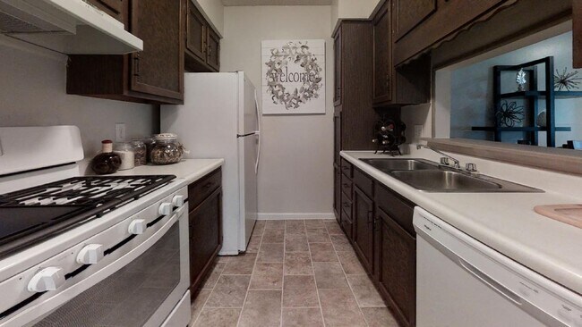 Cocina espaciosa con gabinetes de madera natural, estufa y espacio de encimera abierto, creando un ambiente de cocina hogareño. - Wilshire Apartments