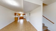 Located at 101 Embassy Ct in Muldraugh, Kentucky, this two-story, two-bedroom, two-bathroom unit offers a practical and well-organized layout across two evenly distributed floors. The main level opens into a combined dining and living area, creating a comfortable shared space anchored by light-toned tile flooring. The kitchen is efficiently designed in an L-shaped configuration, featuring warm oak cabinetry with ample upper and lower storage, light countertops, a white electric range, dishwasher, refrigerator, and a window that brings in natural light. A bathroom on this level includes a vanity with wood cabinetry and tile flooring. The upper floor houses both bedrooms, each finished with neutral wall-to-wall carpeting and individual closets with built-in shelving. The bedrooms receive natural light through windows with views of surrounding greenery. A full bathroom on this floor includes a tub-shower combination. Additional highlights include four closets throughout for generous storage, an in-unit laundry area, and two staircases connecting the floors. The clean, white walls and consistent finishes throughout give the space a simple, functional character well-suited for everyday living.