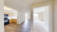 Located at 1490 7th St NW in Washington, DC's vibrant Shaw neighborhood, this one-bedroom, one-bathroom unit offers a well-organized single-floor layout designed for efficient urban living. The kitchen is a standout feature, outfitted with light maple cabinetry extending to the ceiling, black appliances including a range, microwave, and dishwasher, and a clean white countertop breakfast bar with pendant lighting overhead. Light hardwood-style flooring runs throughout the main living and kitchen areas, lending warmth to the space. The bedroom is carpeted and benefits from a large floor-to-ceiling sliding glass window that floods the room with natural light and frames views of the surrounding Washington, DC cityscape. Neutral, warm-toned walls throughout the unit create a bright and cohesive aesthetic. The bathroom is thoughtfully designed with accessibility in mind, featuring stainless steel grab bars at the tub, shower, and toilet, a combination shower/tub with a handheld showerhead, tile flooring, and a wood-toned vanity with a white countertop. The unit's efficient floor plan, visible in the dollhouse view, connects all rooms in a logical flow, making the most of the available space in a prime urban DC location.