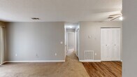 Located at 3110 Greystone Ln in Albany, Georgia, this single-floor, 2-bedroom, 1-bathroom home offers a practical and comfortable layout with a variety of functional spaces. The galley-style kitchen is well-equipped with white cabinetry lining both walls, light-toned countertops, a double basin sink, and white appliances including an electric range and refrigerator, all set atop durable hardwood-style flooring. The kitchen flows into a versatile living area that also features hardwood-style flooring, a ceiling fan with light fixture, and a built-in closet with louvered bifold doors. Both bedrooms are carpeted and include ceiling fans for year-round comfort. The spacious primary bedroom features a wide louvered bifold closet and neutral gray walls, offering a calm and functional retreat. The second bedroom benefits from a window that invites natural light. Each bedroom is served by dedicated closet space. The full bathroom includes a tub-shower combination with a handheld showerhead and chrome fixtures. Neutral gray walls, white trim, and textured ceilings are consistent throughout, creating a cohesive and clean aesthetic. A connecting hallway ties the layout together efficiently, making this home a well-organized and functional living space.