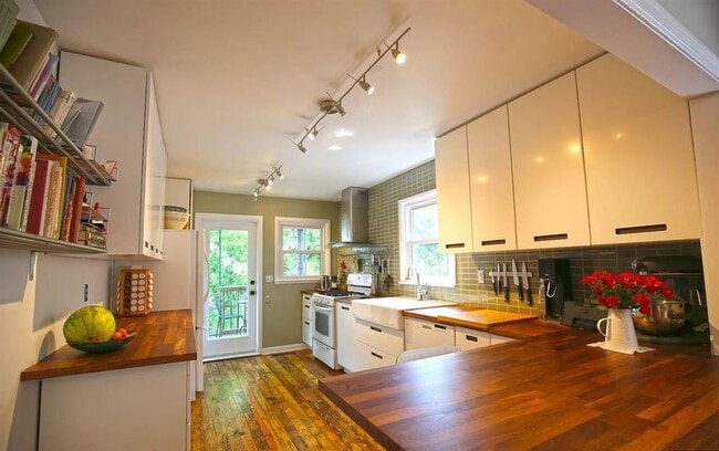 The kitchen has been lovingly updated with Maple countertops, a Breakfast Bar with seating for 4, a white Farm Sink, subway tile backsplash AND soft-close IKEA Cabinets - 903 Highland Rd