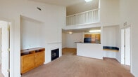 Located at 7612 Timberlake Rd in Lynchburg, Virginia, this two-story residence offers a well-designed layout combining comfort and functionality across both levels. The main living area immediately impresses with its soaring vaulted ceilings and a dramatic upper-level balcony overlook, lending a sense of openness and grandeur to the space. A classic fireplace with a white mantle serves as the focal point of the living room, flanked by built-in shelving and a warm wood media cabinet. Plush carpeting flows throughout the living areas, adding a cozy feel underfoot. The kitchen is efficiently designed with warm honey-toned wood cabinetry, dark countertops, tile flooring, and a full suite of black appliances including a refrigerator, range, microwave, and dishwasher. An electrical panel is conveniently accessible near the kitchen entry. The upper level features a loft-style landing that overlooks the main living area below, along with generously sized bedrooms, each with plush carpet and double-door closets. Multiple windows allow natural light to fill the rooms. Bathrooms are outfitted with stone-look tile flooring, warm wood vanities, and full tub-shower combinations, offering a practical and polished finish throughout.