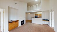 Located at 7612 Timberlake Rd in Lynchburg, Virginia, this two-story residence offers a well-designed layout combining comfort and functionality across both levels. The main living area immediately impresses with its soaring vaulted ceilings and a dramatic upper-level balcony overlook, lending a sense of openness and grandeur to the space. A classic fireplace with a white mantle serves as the focal point of the living room, flanked by built-in shelving and a warm wood media cabinet. Plush carpeting flows throughout the living areas, adding a cozy feel underfoot. The kitchen is efficiently designed with warm honey-toned wood cabinetry, dark countertops, tile flooring, and a full suite of black appliances including a refrigerator, range, microwave, and dishwasher. An electrical panel is conveniently accessible near the kitchen entry. The upper level features a loft-style landing that overlooks the main living area below, along with generously sized bedrooms, each with plush carpet and double-door closets. Multiple windows allow natural light to fill the rooms. Bathrooms are outfitted with stone-look tile flooring, warm wood vanities, and full tub-shower combinations, offering a practical and polished finish throughout.