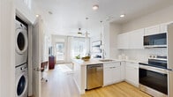 Located on Dry Creek Drive in Longmont, Colorado, this one-bedroom, one-bathroom residence offers a well-designed, single-floor layout that maximizes every square foot. The open-concept living and kitchen area is anchored by a sleek white kitchen featuring shaker-style cabinetry, light quartz countertops, a peninsula with bar seating, and a full suite of stainless steel appliances including a refrigerator, range, microwave, and dishwasher. Pendant lighting above the peninsula adds a modern touch, while light-toned hardwood flooring flows seamlessly throughout the entire space, enhancing the bright, airy atmosphere. The living area benefits from large windows dressed with white curtains and blinds, allowing abundant natural light to fill the room. A ceiling fan provides year-round comfort. The spacious bedroom is well-lit by multiple windows and features the same warm hardwood flooring, a ceiling fan, and ample wall space. A dedicated closet provides convenient storage. The full bathroom is finished with white subway tile surrounding a soaking tub and shower, a single-sink vanity with white cabinetry, quartz countertop, and recessed lighting. Clean, neutral tones and consistent modern finishes create a cohesive, move-in-ready aesthetic throughout this Longmont residence.
