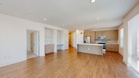 Located at 1997 S Acoma St in Denver, Colorado, this single-floor residence offers a well-designed, modern living environment with an emphasis on open space and natural light. The open-concept main living area features warm hardwood-style flooring, recessed lighting, and large floor-to-ceiling windows that flood the space with abundant natural light while offering views of the surrounding Denver neighborhood. A set of sliding glass doors provides direct access to a private balcony, extending the living space outdoors. The contemporary kitchen is a standout feature, equipped with light wood cabinetry, a stainless steel appliance suite including a refrigerator with ice maker, microwave, and range, complemented by a sleek tile backsplash and a generous center island with a white countertop and integrated sink. A built-in shelving unit and desk area seamlessly connect the kitchen and living zones, offering practical storage and workspace solutions. The bedroom is carpeted for comfort and includes sliding glass door access to a balcony, along with a walk-in closet outfitted with adjustable shelving and hanging rods. The bathroom features an elegant glass-enclosed shower with marble-style tile. An additional walk-in closet with dual hanging rods provides generous storage. The overall aesthetic is clean, bright, and modern throughout.