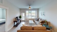 Located at 652 Herrons Ferry Rd in Rock Hill, SC, this well-appointed single-floor residence offers a thoughtfully designed open-concept layout that seamlessly connects the main living areas. The kitchen is a standout feature, equipped with stainless steel appliances including a refrigerator with ice and water dispenser, an electric range, and a built-in microwave. Soft gray shaker-style cabinetry reaches toward the ceiling, providing generous storage, while crisp white quartz countertops extend to a center island with a double sink and bar seating — ideal for casual dining or entertaining. Light wood-style flooring flows throughout the main living areas, contributing to a bright, cohesive aesthetic. The open living room is generously sized, bathed in natural light from large windows and a glass door that opens to a balcony with outdoor views. Two comfortable bedrooms feature plush carpeting, ceiling fans, and ample natural light. Each is served by a full bathroom finished with light tile flooring, gray vanity cabinetry, white quartz countertops, and a tub-shower combination. One bathroom includes access to a walk-in closet with built-in shelving. The overall ambiance is modern, clean, and inviting throughout.