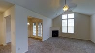 This single-floor, three-bedroom, two-bathroom residence at The Grandover offers a well-designed layout with notable architectural character. The living area serves as a central highlight, featuring vaulted ceilings that lend a sense of spaciousness and airiness to the room. A ceiling fan with a light fixture is mounted at the peak, complementing the room's vertical scale.

A wood-manteled fireplace anchors one wall of the living space, providing a classic focal point. Large windows, including a tall multi-pane window, flood the area with natural light and offer views of the surrounding greenery. Adjacent to the main living area, French doors open into a secondary room or sunroom, which also benefits from generous window coverage, further enhancing the home's brightness.

Soft carpeting extends throughout the living spaces, contributing to a comfortable and warm ambiance. The neutral color palette of the walls and flooring creates a versatile backdrop suitable for a variety of interior styles. Overall, this residence combines functional single-floor living with inviting architectural details that make it feel open, light-filled, and welcoming.