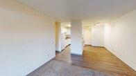 This single-floor residence offers a practical and comfortable layout designed for everyday living. The open living area features a combination of soft carpeting and wood-look vinyl flooring, with a sliding glass door that opens to a private balcony, allowing natural light to fill the space and providing outdoor views. A second carpeted room with a sliding window similarly benefits from natural light and greenery views outside.

The kitchen is well-appointed with crisp white cabinetry, rich stone-look countertops, and light wood-look vinyl flooring. It includes a full suite of white appliances — refrigerator, dishwasher, and range — along with a double-basin sink. Track lighting in the adjoining dining or entry area adds a modern touch.

The bedrooms are carpeted and generously sized, each featuring sliding windows, baseboard heating, and ample wall space. One bedroom includes built-in closets and direct access to a full bathroom, which is equipped with a bathtub and shower combination, safety grab bars, and tile flooring. A second bathroom offers a vanity with stone-look countertops and tile flooring. Throughout the residence, neutral tones and clean finishes create a calm, move-in-ready atmosphere.