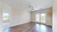 Located at 120 Buckhill Village Dr in Burlington, NC, this well-appointed single-story home offers three bedrooms, two bathrooms, and a thoughtfully designed layout across a comfortable footprint. A welcoming entrance leads down a hallway into a bright, open-concept living, dining, and kitchen area. The kitchen is a standout feature, boasting white cabinetry, granite countertops, stainless steel appliances including a refrigerator, microwave, and range, and a central island ideal for meal prep or casual dining. Rich hardwood-style flooring flows throughout the main living areas, adding warmth and continuity. The spacious living room is bathed in natural light and features a ceiling fan and French doors that open onto a private patio with outdoor views. The bedrooms are carpeted for comfort, with the generously sized primary bedroom offering a walk-in closet with built-in wire shelving. Additional bedrooms also feature closets, and the home includes an impressive seven closets in total, providing exceptional storage. Both bathrooms are finished with tub/shower combos, granite-topped vanities, and wood-style flooring. A dedicated laundry room and pantry add everyday convenience, completing this functional and well-designed home.