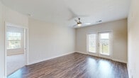 Located at 120 Buckhill Village Dr in Burlington, NC, this well-appointed single-story home offers three bedrooms, two bathrooms, and a thoughtfully designed layout across a comfortable footprint. A welcoming entrance leads down a hallway into a bright, open-concept living, dining, and kitchen area. The kitchen is a standout feature, boasting white cabinetry, granite countertops, stainless steel appliances including a refrigerator, microwave, and range, and a central island ideal for meal prep or casual dining. Rich hardwood-style flooring flows throughout the main living areas, adding warmth and continuity. The spacious living room is bathed in natural light and features a ceiling fan and French doors that open onto a private patio with outdoor views. The bedrooms are carpeted for comfort, with the generously sized primary bedroom offering a walk-in closet with built-in wire shelving. Additional bedrooms also feature closets, and the home includes an impressive seven closets in total, providing exceptional storage. Both bathrooms are finished with tub/shower combos, granite-topped vanities, and wood-style flooring. A dedicated laundry room and pantry add everyday convenience, completing this functional and well-designed home.