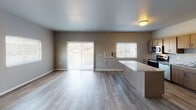 This single-floor unit located at 20th Street South in Brookings, South Dakota, presents a clean, modern interior with a neutral color palette throughout. The open-concept living and dining area is finished with light-toned luxury vinyl plank flooring, offering a bright and welcoming atmosphere enhanced by sliding glass door access and multiple windows that bring in natural light and outdoor views.

The kitchen is well-equipped with a full suite of stainless steel appliances, including a refrigerator, electric range, over-the-range microwave, and dishwasher. Light wood cabinetry provides ample storage, while granite-style countertops add a contemporary touch. A breakfast bar peninsula connects the kitchen to the living area, reinforcing the open layout.

Bedrooms are carpeted for comfort and feature generous proportions, with at least one room offering a walk-in closet with built-in shelving. Windows in each bedroom allow for natural light and ventilation. The bathrooms include full tub-shower combinations with chrome fixtures, wood-look vinyl flooring, and vanities with stone-style countertops. The overall design emphasizes functional, modern living in a clean and well-maintained setting.
