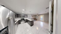 This well-appointed 1-bedroom, 1-bathroom unit delivers a modern living experience with thoughtful design details throughout. The open-concept kitchen serves as the centerpiece of the space, featuring dark wood-grain cabinetry, crisp white quartz countertops, a full suite of stainless steel appliances — including a refrigerator, range, microwave, and dishwasher — and a peninsula island illuminated by stylish pendant lighting. Marble-look porcelain tile flooring runs seamlessly throughout the entire unit, lending a clean, cohesive aesthetic. The bedroom is a comfortable retreat, painted in soothing slate blue and fitted with a ceiling fan, natural light from a window with sheer curtains, and convenient access to both a dedicated closet and an additional room. The walk-in closet offers multi-level chrome hanging rods for organized storage. The bathroom is finished with the same marble-look tile and features a glass-enclosed walk-in shower with elegant marble-patterned wall tile. A stacked in-unit washer and dryer adds everyday convenience. Recessed lighting and a neutral color palette tie the space together for a refined, contemporary feel.