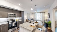 Located at 1601 Scottsdale Ln in Austin, TX, this thoughtfully designed one-bedroom, one-bathroom residence offers a contemporary open-concept layout across a single floor. The kitchen and living area flow seamlessly together, anchored by a granite-topped island with an undermount sink and seating for two, illuminated by elegant pendant lights. Dark-toned cabinetry, a white subway tile backsplash, and a full suite of stainless steel appliances—including a refrigerator, range, and microwave—complete the kitchen's modern aesthetic. Hardwood-style flooring runs throughout the space, adding warmth and continuity.

The living room is a standout, featuring a ceiling fan, a large French door that invites natural light, and a distinctive sliding barn door that adds architectural character. The bedroom is a comfortable retreat with natural light from large windows, a ceiling fan, and ample space for furnishings. The bathroom echoes the home's refined finishes with a granite-topped vanity, wood-toned cabinetry, a glass-enclosed shower, and wood-style flooring. The entrance and hallway provide a clean, functional transition throughout. The overall ambiance is modern, bright, and cohesive.