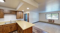 This single-floor residence offers a practical and well-organized layout designed for comfortable everyday living. The heart of the home is an open-concept kitchen and living area, where warm oak cabinetry with ample upper and lower storage lines the kitchen walls. White appliances, including a refrigerator, range, and oven, are complemented by a double sink and a peninsula with a light-colored countertop that provides additional workspace and separates the kitchen from the living area. The living space features durable wood-look flooring that transitions into plush carpet, and is fitted with a ceiling fan and baseboard heating throughout. A textured ceiling adds a classic touch to the shared living space. The two bedrooms are carpeted and well-lit by natural light through slatted windows, with baseboard heaters ensuring year-round comfort. One bedroom includes access to a walk-in closet with built-in shelving, while another features a wall-mounted storage cabinet. The full bathroom is finished with tile flooring, a wood-toned vanity, and a tub and shower combination enclosed by sliding glass doors. A dedicated entry door and interior closet complete this functional and efficiently designed space.