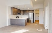 Located at 10023 104 Street NW in Edmonton, Alberta, this thoughtfully designed 2-bedroom, 1-bathroom unit offers a clean, contemporary aesthetic throughout. Light-toned hardwood flooring flows consistently across the entire space, complementing the crisp white walls and creating a bright, cohesive atmosphere.

The kitchen is a standout feature, showcasing rich dark wood cabinetry that extends floor to ceiling, contrasted by a white quartz countertop and a white tile backsplash. A peninsula provides additional prep space, while a full suite of stainless steel appliances — including a refrigerator, range, over-the-range microwave, and dishwasher — ensures modern functionality.

A central hallway connects the living areas to the two bedrooms, each closet-equipped and filled with natural light from large windows that frame views of the Edmonton skyline. The primary bedroom offers a comfortable footprint, while the second bedroom is well-suited as a guest room or home office, both maintaining the same bright, airy character found throughout the unit.

The bathroom features a full soaker tub and shower combination, accented by floor-to-ceiling neutral grid tile and chrome fixtures, offering a clean and timeless finish. Two dedicated closets provide practical storage solutions. Overall, the unit presents a polished, move-in-ready interior with modern finishes in a well-connected Edmonton location.