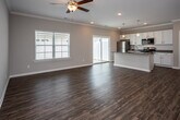 Located at 6412 Shallowford Rd in Chattanooga, Tennessee, this single-story home offers a clean, modern aesthetic throughout. Rich hardwood-style flooring runs continuously across the living areas, complemented by crisp white trim, crown molding, and neutral gray walls that create a bright, welcoming atmosphere.

The open-concept living and kitchen area forms the heart of the home, anchored by a ceiling fan with a light fixture and recessed lighting. The kitchen is well-equipped with white shaker-style cabinetry, granite countertops, a classic subway tile backsplash, stainless steel appliances including a range, microwave, and refrigerator, and a central island with a sink. An adjacent walk-in pantry provides generous storage.

The bedrooms are comfortably proportioned, each featuring ceiling fans, hardwood-style flooring, and closet space, including a walk-in closet with a full clothing rod system. The hallways connect the rooms with a functional and open flow.

The bathrooms maintain the home's consistent style, featuring white cabinetry, granite-topped vanities, and natural light from windows. The primary bathroom includes a double-sink vanity with ample counter space. Throughout, the home presents a move-in-ready condition with modern, cohesive finishes ideal for comfortable everyday living.