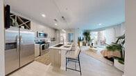 Located at 1114 W Carmen St in Tampa, FL, this well-appointed 2-bedroom, 2-bathroom residence offers a thoughtfully designed single-floor layout with modern finishes throughout. The open-concept living and kitchen area serves as the heart of the home, featuring light wood-tone cabinetry, stainless steel appliances, a subway tile backsplash, and a central island with bar seating — ideal for both cooking and entertaining. Light wood-style flooring runs throughout the main living space, amplifying the bright, airy atmosphere. The living room is bathed in natural light from large French doors that open to a private balcony with views of lush outdoor greenery. The primary bedroom offers a comfortable, carpeted retreat with soft natural light. The second bedroom is equally functional, with a window, carpet flooring, and ample space for flexible use. Two well-appointed bathrooms serve the unit — one featuring a glass-enclosed walk-in shower with clean white tile, and the other offering a full soaking tub and shower combo. Both bathrooms are finished with light wood vanities and white quartz countertops. Two closets provide generous storage. The overall design aesthetic is clean, contemporary, and bright, making this Tampa residence a modern urban retreat.