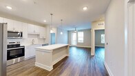 Located at 2002 Wilson Ave in Panama City, FL, this well-appointed 2-bedroom, 2-bathroom single-floor residence offers a thoughtfully designed open-concept layout. The combined living, dining, and kitchen area forms the heart of the home, showcasing rich wood-look flooring that flows seamlessly throughout. The modern kitchen is outfitted with crisp white cabinetry reaching to the ceiling, a classic subway tile backsplash, stainless steel appliances including a side-by-side refrigerator with ice maker, electric range, and built-in microwave, plus a central island with pendant lighting that doubles as additional prep and dining space. The living area benefits from natural light streaming through large windows and a sliding glass door that opens to a private patio, complemented by a ceiling fan overhead. Both bedrooms are generously sized, each featuring ceiling fans, natural light from windows with outdoor views, and hardwood-style flooring. The primary bathroom offers a dual-sink vanity with white cabinetry, a large mirror, and direct access to a well-organized walk-in closet. A dedicated laundry room houses a full-size Whirlpool washer and dryer with overhead wire shelving. Two closets provide ample storage throughout the residence.