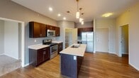 This single-floor residence at 3227 43rd Ave NE in Bismarck, North Dakota offers a thoughtfully designed open-concept layout. The kitchen serves as a central hub, showcasing rich dark-stained cabinetry, light quartz countertops, and a full suite of stainless steel appliances including a gas range, built-in microwave, and French door refrigerator. A center island with an undermount sink provides additional prep space and is highlighted by stylish pendant lighting overhead. Recessed lighting and wood-look flooring extend throughout the main living area, which flows seamlessly toward a sliding glass door leading to a private balcony with open outdoor views.

The bedroom areas feature plush carpeting and generous closet space with built-in shelving for organized storage. Bathrooms are finished with dark wood vanities, light countertops, and full tub-shower combinations set on wood-look flooring, maintaining a consistent and clean aesthetic throughout. A dedicated in-unit laundry space accommodates full-size washer and dryer units, adding everyday convenience. The overall ambiance is modern and neutral, with a cohesive color palette that creates a welcoming, move-in-ready environment.